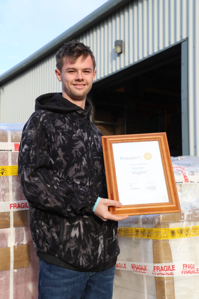 Harry outside the Jo Bird warehouse holding his certificate.